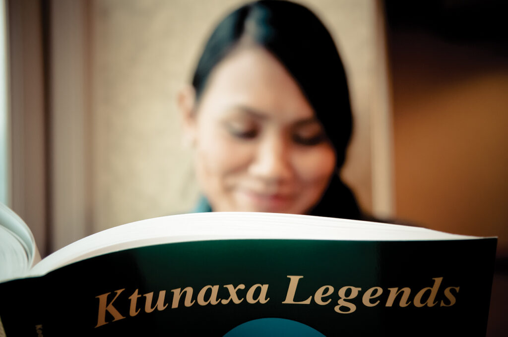 Woman reading "Ktunaxa Legends," discovering the history and traditions of the Ktunaxa people.
