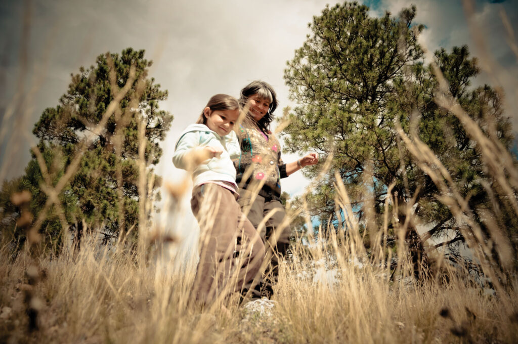 A woman and girl walk together with wild grass in the foreground.