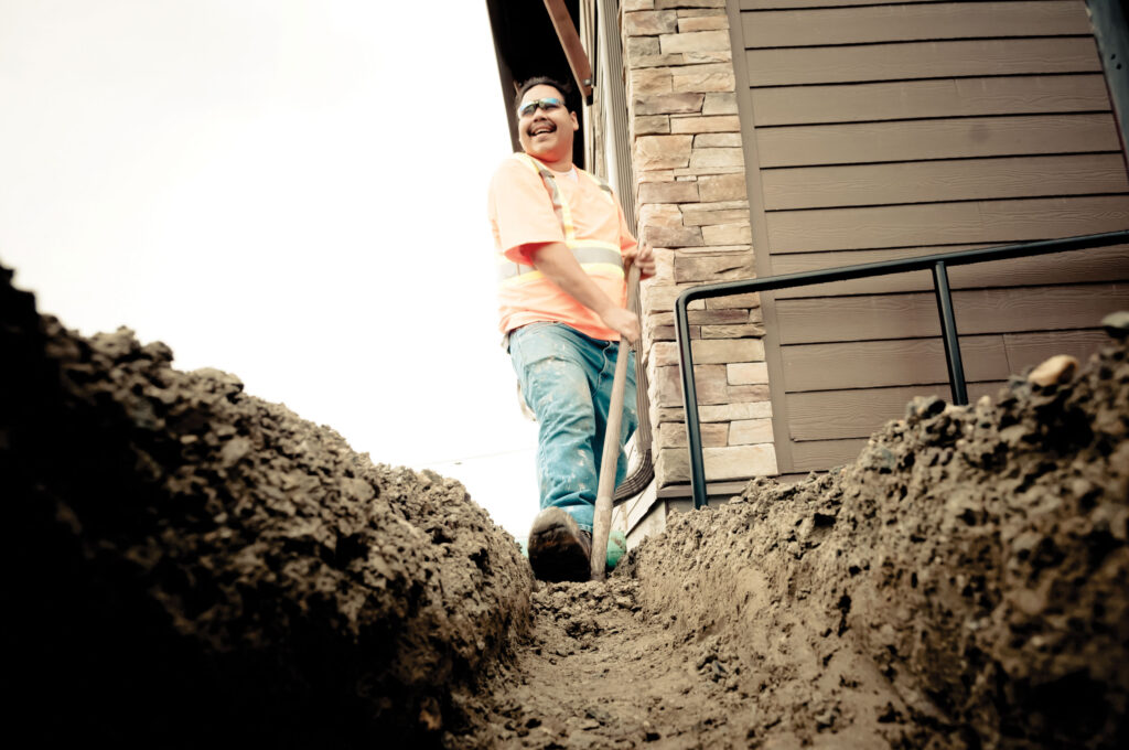 A man digging a trench next to a building