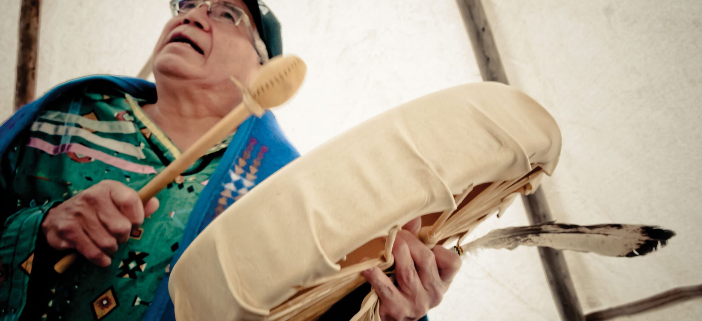A man holding a drum in a teepee